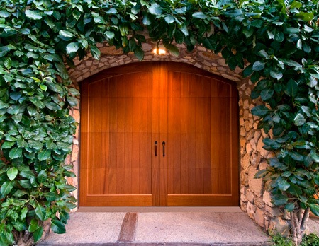 Wood Garage Doors Surrounded by Stone and Ivy