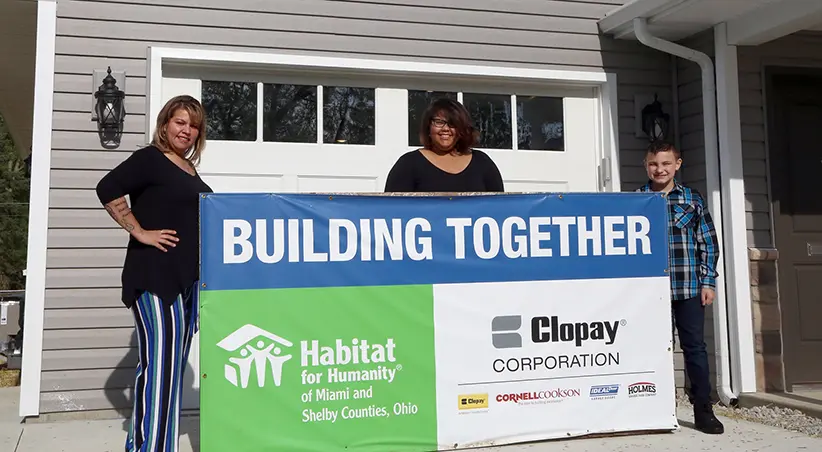 Marie and family in front of the Habitat for Humanity banner