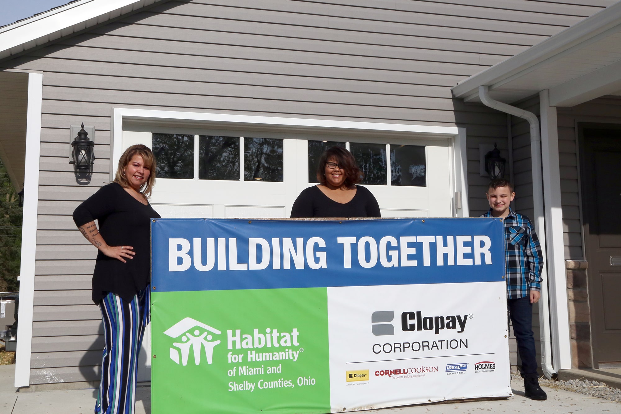 Marie and family in front of the Habitat for Humanity banner